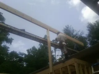 Carpenter setting a ridge beam over a new addition frame — Ice Dam Removal by Roofing Brothers in Milnor