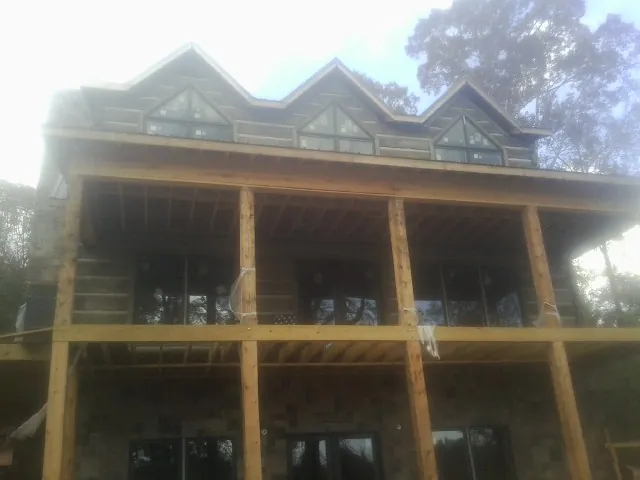 Dormers and porch framing on a large log home under construction — Roof Coating work by our crew in Milnor