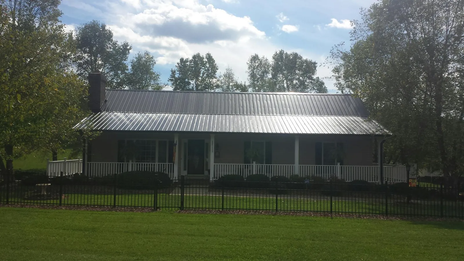 Gray metal roof on a brick ranch with a full width front porch — Gutter Guard Installation work by our crew in Milnor